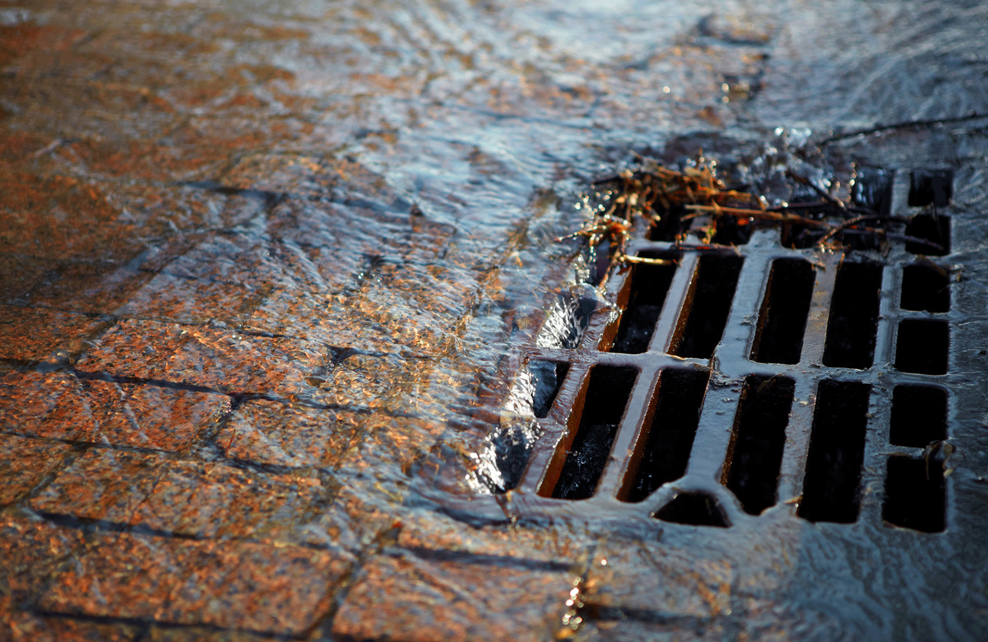 a storm drain with rain water pouring in