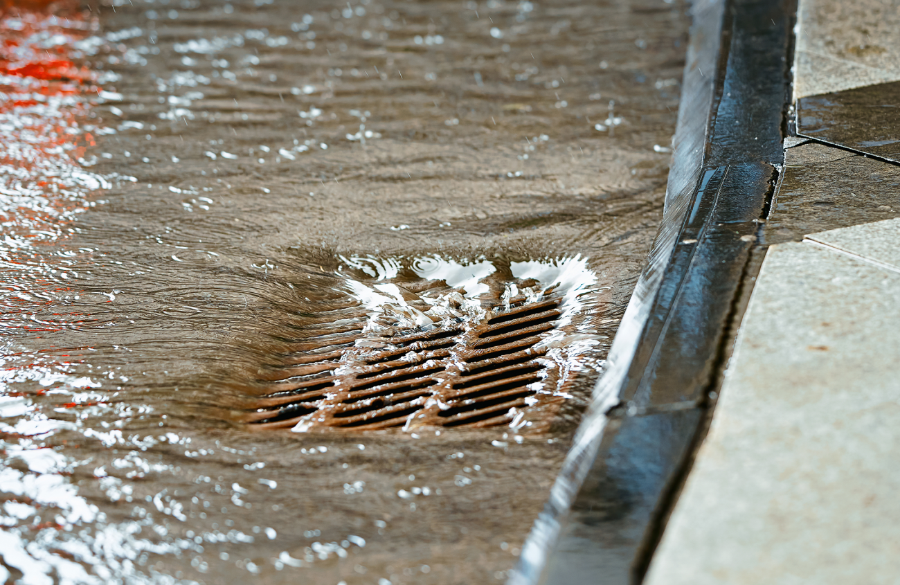 a storm drain with rainwater pouring in