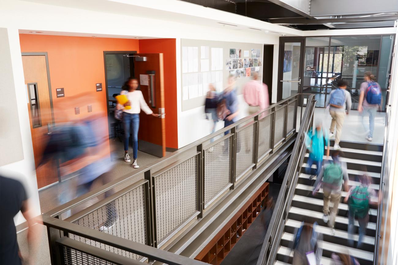 Students moving through a busy modern high school hallway, representing the importance of data-driven school building capacity analysis for strategic resource planning.